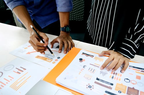 People huddling round a table with graphs and analytics